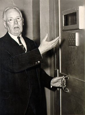 [Warden James A. Johnston of Alcatraz Prison pointing to a door which kept rioting prisoners from escaping]