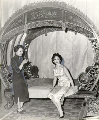 [Mrs. James Loo and Miss Angie Wong inspecting a ancient Chinese bed]