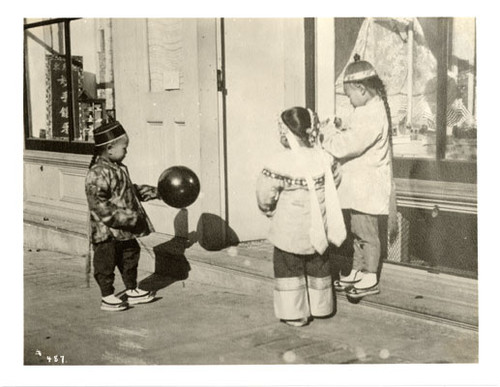 [Three young children playing outside a store in Chinatown]