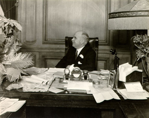 [Mayor James Rolph, Jr. sitting behind his desk in the mayor's office]