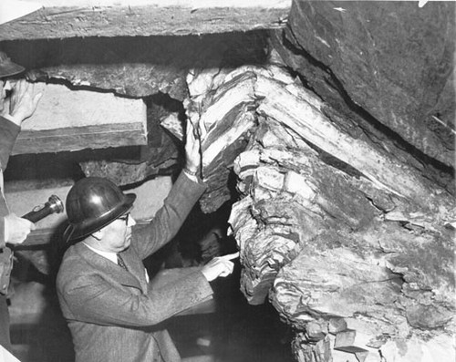 [C.H. Purcell, Chief Engineer, pointing at rock inside the tunnel on Yerba Buena Island during San Francisco-Oakland Bay Bridge construction]