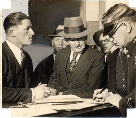 [Inspector Allen McGinn, in the center, Chas A. Simpson, first from left, two unidentified men, and a police officer]