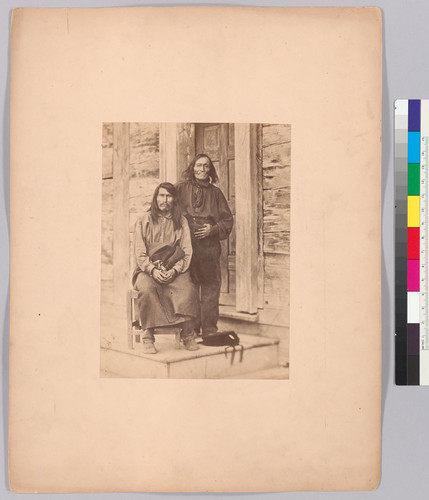 [Two Native American men, one standing and one seated.]