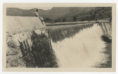 Young man seated above spillway at Boulder Creek diverting dam