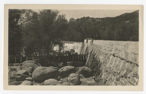 Water spilling over the top of an unidentified dam, with San Diego flume in foreground