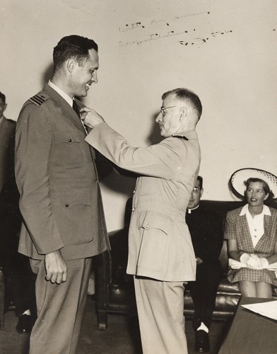 [U.S. Admiral Paul Lee, Chief of the U.S. Office of Naval Research, presenting Roger Revelle with a commendation from the Secretary of the Navy for his work on Operation Crossroads; Ellen Clark Revelle (Mrs. Roger Revelle) in background]