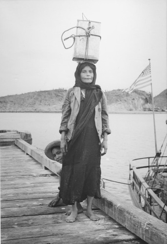 Woman in Guaymas is balancing a load of about 40 pounds of fresh clams, which were converted into a welcome stew by the cook of the R/V E.W. Scripps. Gulf of California Expedition, 1939
