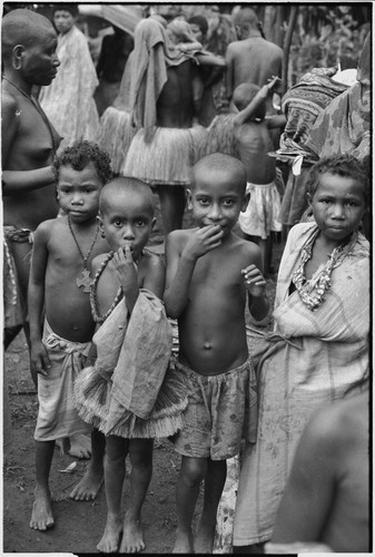 Mortuary ceremony, Omarakana: children, boy (l) wears cross medal of type given by Allied forces to local men during World War II