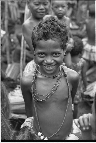 Mortuary ceremony, Omarakana: smiling girl wears turtle shell earrings and mourning necklace which may hold fingernails or other relics of the deceased