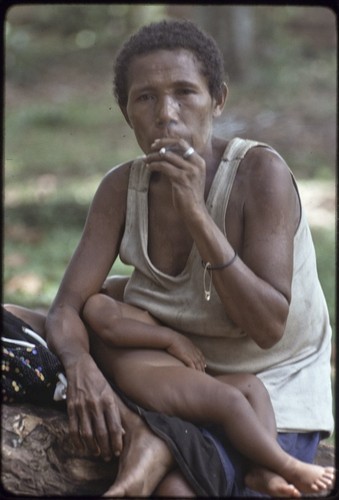 Woman smoking, her sleeping infant on her lap