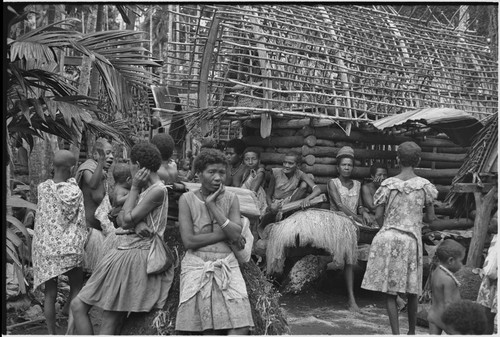 Mortuary ceremony, Omarakana: women by partially full yam house, one holds a skirt for ritual exchange