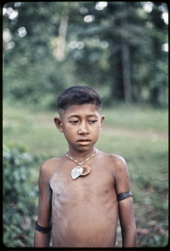 Boy with necklaces, woven armbands, and talcum powder on chest