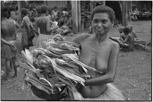 Mortuary ceremony: woman carries banana leaf bundles (wealth items) in basket