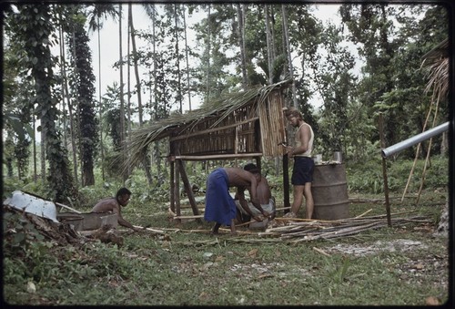 Men, including Edwin Hutchins, construct a hen house