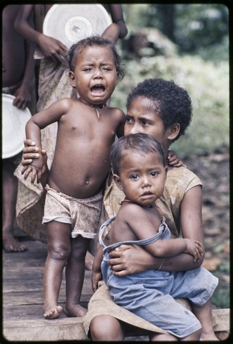 Crying children, held by an older girl