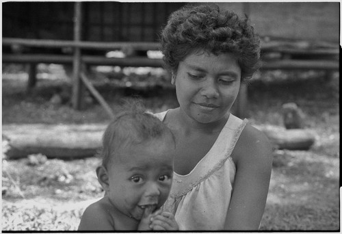 Baby, looking at camera, sits on young woman's lap