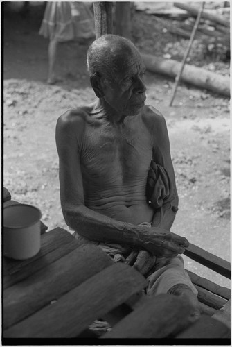 Elderly man sits on shady veranda