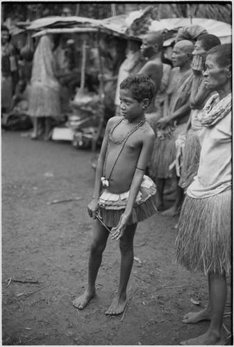 Mortuary ceremony, Omarakana: girl wearing short fiber skirt and mourning necklace (may hold fingernails or other relics of the deceased)