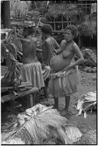 Mortuary ceremony: pregnant woman wearing fiber skirt, next to taro, skirts, banana leaf bundles (wealth items)