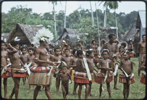 Dance: Motabasi (left) with feathers in hair, dancers wear fiber skirts and carry flattened pandanus leaves for circle dance