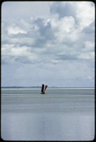 Canoe under sail in lagoon, sail has wide vertical strips