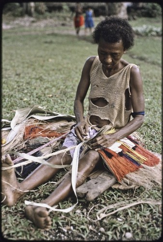 Weaving: woman makes colorful skirt from dyed banana fibers, tying them to cord held around her waist and foot