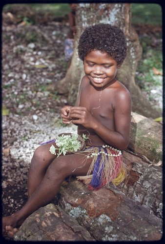 Child making a garland of small flowers