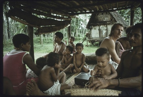 Edwin Hutchins and other people seated under a house, tape recorder (center)