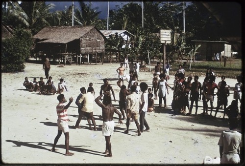 Manus: men playing rugby, referee in striped shirt blows whistle, small group of spectators