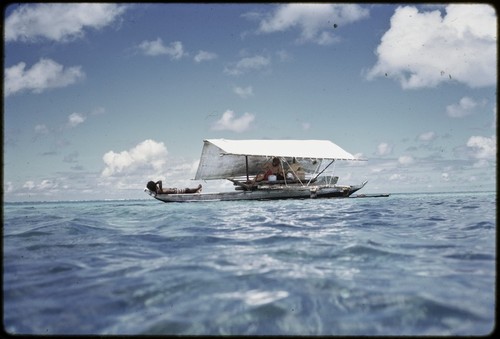 Manus: canoe with shade, Kusunan Kumayon on bow, anthropologist Geoffrey M. White under canopy, near Pere village