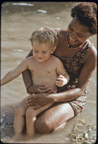 Young woman named Linette taking care of an Australian boy, Butch Holland, plays in water