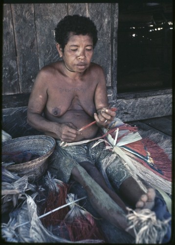 Weaving: woman makes skirt out of banana leaf fibers, some dyed red