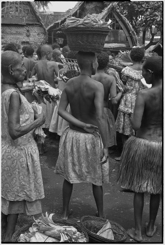 Mortuary ceremony: women exchange banana leaf bundles (wealth items), woman carries full basket on head