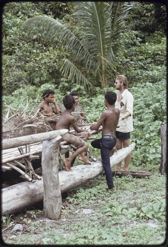 Edwin Hutchins converses with adolescent boys by a large canoe