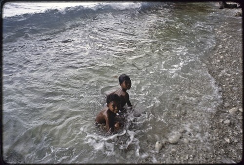 Children play in surf, on the east coast of Kiriwina