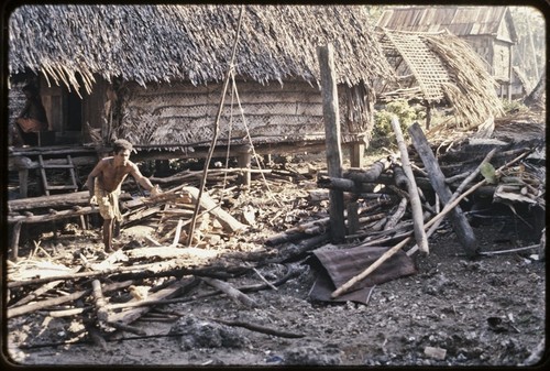 House that has burned down in a fire, Tukwaukwa village on Kiriwina, man piles debris