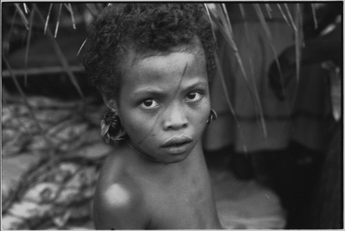 Mortuary ceremony, Omarakana: child with streak of mourning ash across face, wears turtle shell earrings