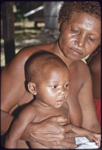 Woman with tattooed arm, holding a young child