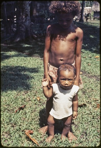 Child stands with an infant