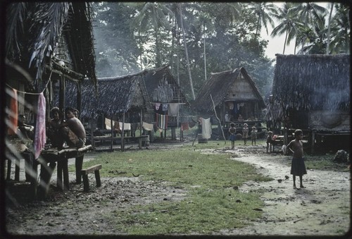 Village scene: people visit on veranda (l), children play in area between houses