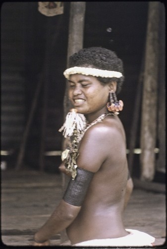 Adolescent girl is beautified, wearing armbands, large turtle shell earrings, flower garlands, and shell necklaces