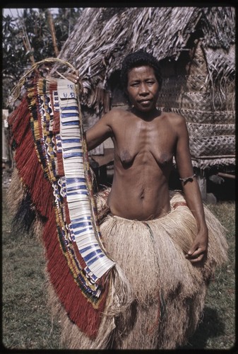 Woman displays decorated fiber skirt valuable, she wears long two-tiered fiber skirt in Wawela village