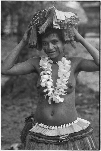 New mother wearing fiber skirt, shell belt, flower garland, skirt valuable on head, and paint on face