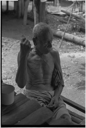 Elderly man sits on shady veranda