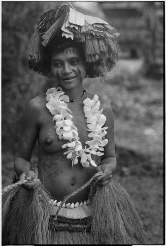 New mother wearing fiber skirt, flower garland, and skirt valuable on head, holds ties for fiber shawl around her waist