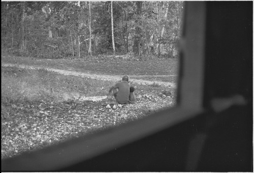 Man sits with young child, seen through a windowframe