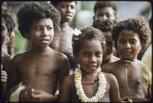 Dance: children beautified with coconut oil and yellow pollen, one child wears red shell necklace and flower garland