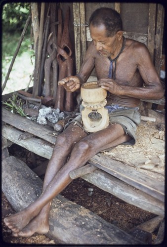 Carving: M'lapokala carving a bowl, other carvings on left are probably for tourist trade