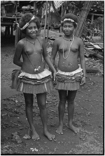 Friendship: adolescent girls wearing short fiber skirts, garlands and necklaces, girl (l) wears mourning necklace