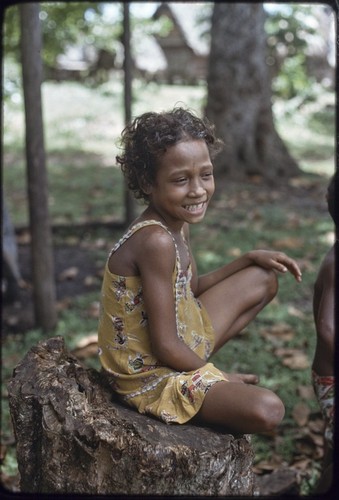 Girl sits on tree stump next to the Hutchins' house